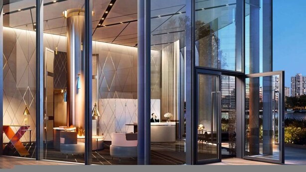 A modern hotel lobby with glass walls, a reception desk, and a seating area. - Waterfront Luxury Apt With Pool Gym Concierge (London)