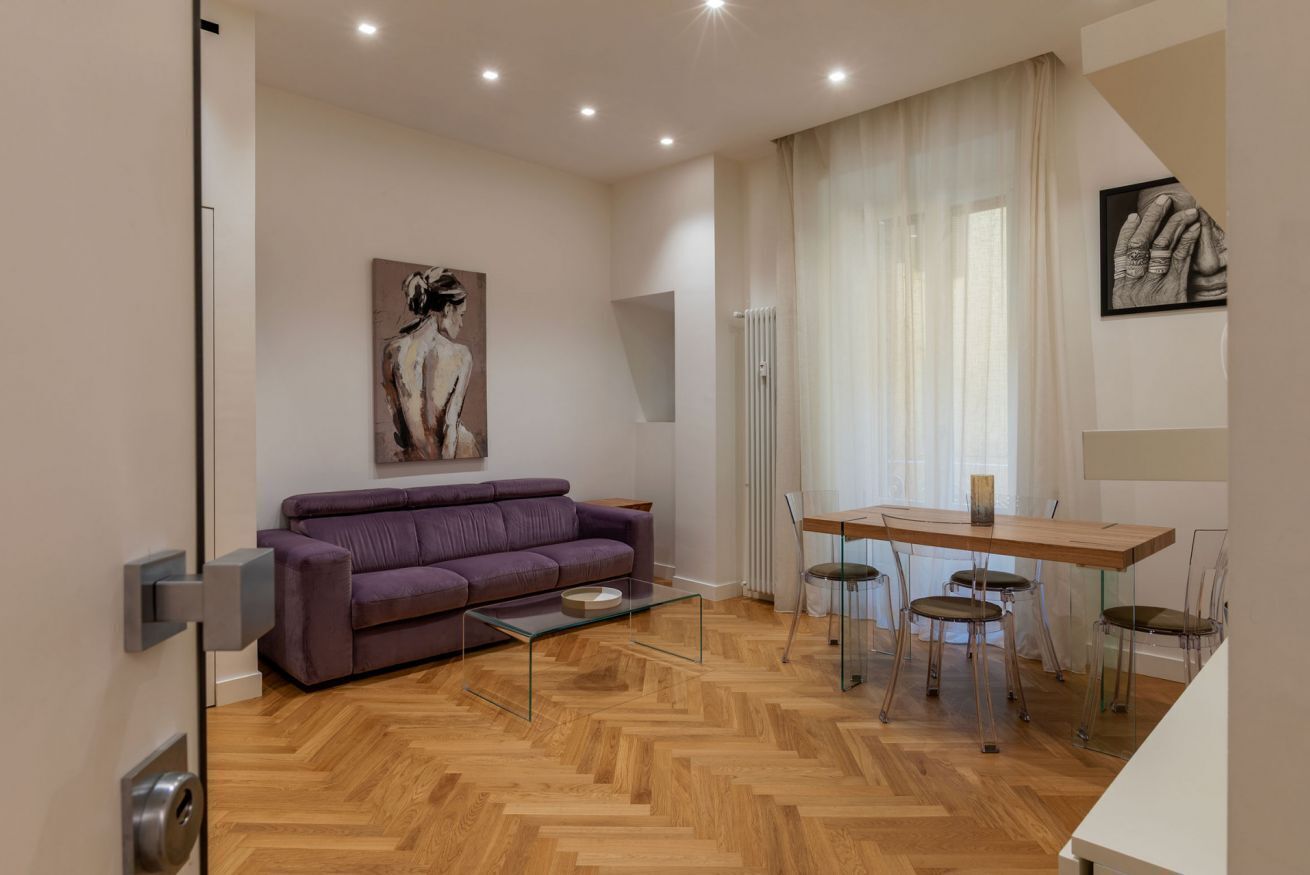 A modern living room with a sofa, a dining table with chairs, and artwork on the walls.