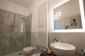 A bathroom with a glass-enclosed shower, a white toilet, a sink with a mirror above it, and a towel rack. - Apartment L'Azdora Ravenna: 600m from the Center and convenient for Cruises (Ravenna)