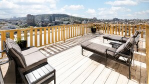 Un terrazzo in legno con posti a sedere all'aperto e vista sulla città.