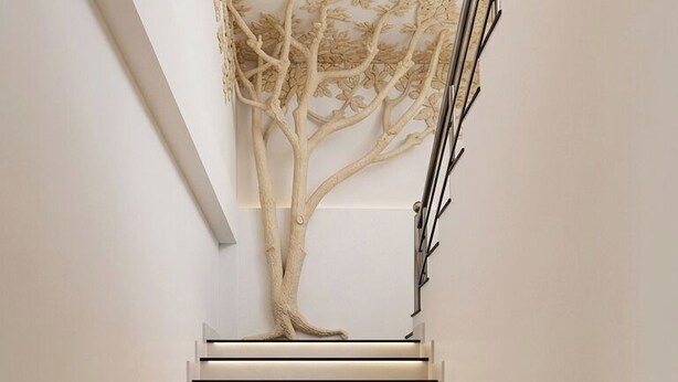 Una escalera moderna con una escultura de árbol en la parte superior.