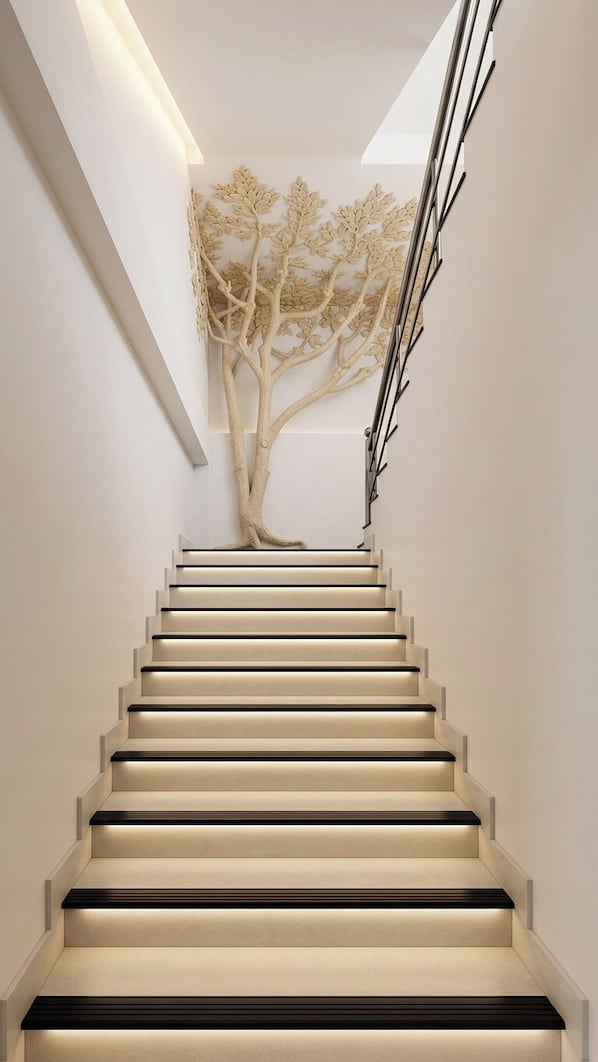 A modern staircase with a tree sculpture at the top.