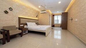 A bedroom with a bed, bedside table, chair, and an air conditioning unit.