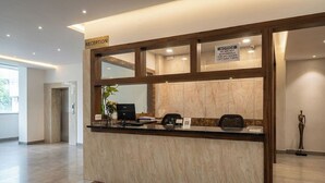 Una recepción con un cartel que indica una política de prohibición de vehículos por 7 días, una computadora y una planta.