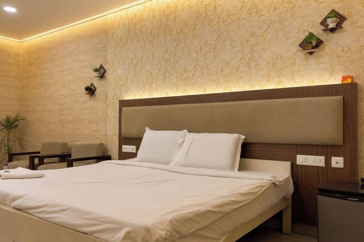 A hotel room with a large bed, a bedside table, a chair, and a small desk.