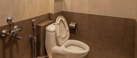 Een badkamer met toilet, douche en spiegel.