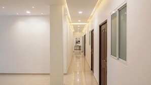 Un pasillo con puertas, piso de baldosas e iluminación empotrada.