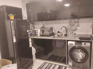 A compact kitchen with a refrigerator, microwave, toaster, sink, and washing machine. - 2-bedroom apartment in marvelous Hurghada with AC and fitness room (Hurghada)