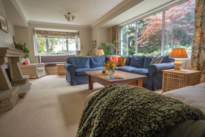 A living room with a blue sofa, a coffee table, and a fireplace. - Wisteria Corner, Large Tranquil Family Home, Spacious, Edge of the Peak District (Chesterfield)