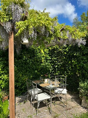 An outdoor dining area with a table and chairs, surrounded by greenery and a wooden pergola. - Wisteria Corner, Large Tranquil Family Home, Spacious, Edge of the Peak District (Chesterfield)