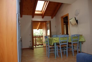 A dining area with a table and chairs, a wooden ceiling, and a view through an open door. - Vrbo Property (Mastellina)