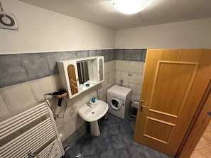 A bathroom with a sink, mirror, towel rack, and a washing machine. - Vrbo Property (Mastellina)