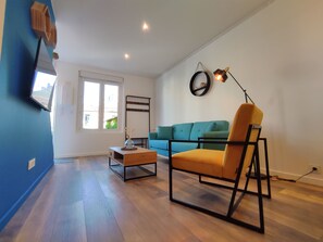 En stue med sofa, stol, sofabord, fjernsyn og lampe.