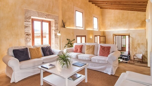 Ein geräumiges Wohnzimmer mit weißen Sofas, einem Couchtisch und einer Steinwand.