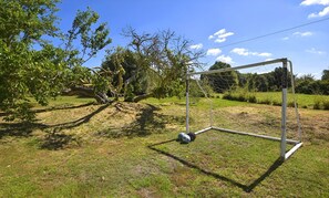 Un but de football installĂ© dans un cadre extĂ©rieur, avec des arbres et de lâherbe.