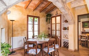 A rustic dining area with a wooden table and chairs, a radiator, and a plant.
