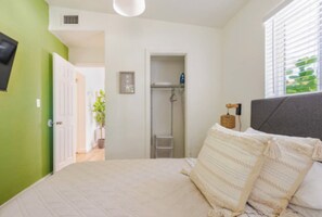Una camera da letto con un letto, un comodino, una finestra con tende e una porta che dà sul bagno.