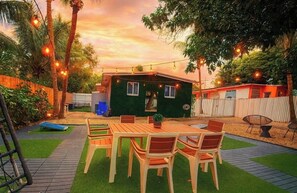 Eine Terrasse mit Tisch und Stühlen, ein kleines Gebäude und Lichterketten.
