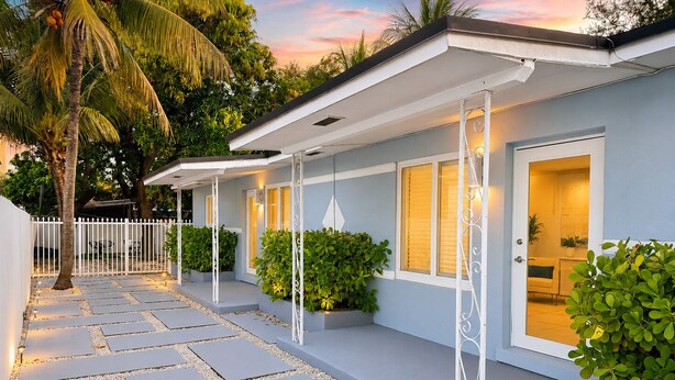 A modern house with a covered porch, potted plants, and a stone pathway. - 4BR Home Near Wynwood + Huge Tropical Yard + BBQ (Miami)
