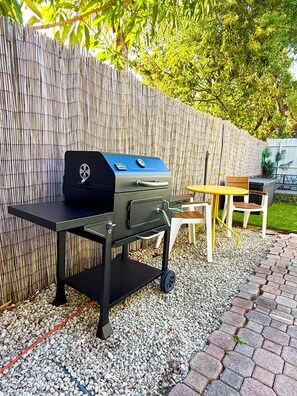 Una griglia per barbecue all'aperto con pannello di controllo, un tavolo e sedie.