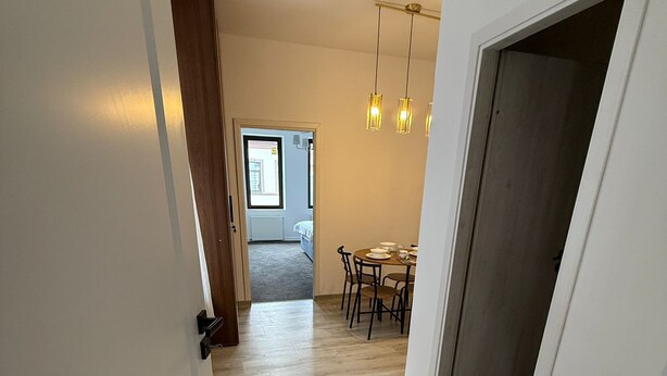 Käytävän lattiassa on puulattia, ja se johtaa ruokailutilaan, jossa on pöytä ja tuolit.
