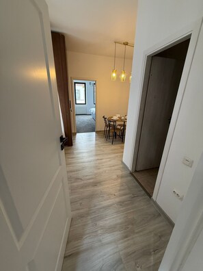 Een gang met houten vloer die uitkomt in een eethoek met een tafel en stoelen.