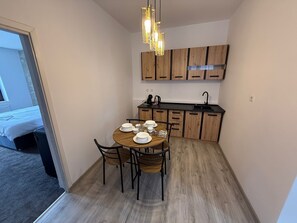 A compact kitchen with wooden cabinets, a dining table set for four, and a hanging light fixture. - Random Studio | Pet-Friendly Stay | Cozy Apartment (Brașov)