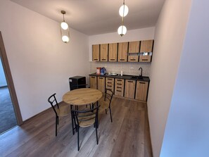 A compact kitchen with wooden cabinets, a round dining table, and two chairs. - Random Studio | Pet-Friendly Stay | Cozy Apartment (Brașov)