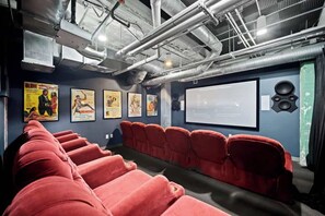 Ein Kino mit roten Sitzen, einer Leinwand und Plakaten an der Wand.