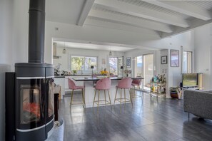 Eine moderne Küche mit einer zentralen Kochinsel, Barhocker, einem Fernseher und einem Kamin.