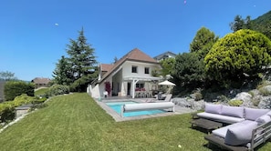 Ein Haus mit Swimmingpool, Terrasse und Gartenmöbeln sowie einem gepflegten Rasen.