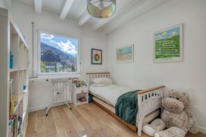 A bedroom with a bed, a crib, a large teddy bear, a desk with a chair, and a window with a view of a house and mountains. -
Luxurious Villa Ella Talloires (Talloires-Montmin)