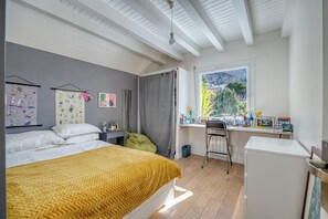 Ein Schlafzimmer mit Bett, Schreibtisch, Stuhl und Fenster mit Blick.