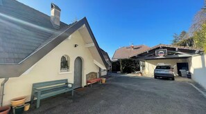 En boligejendom med skrå tag, garage, indkørsel og bænk.