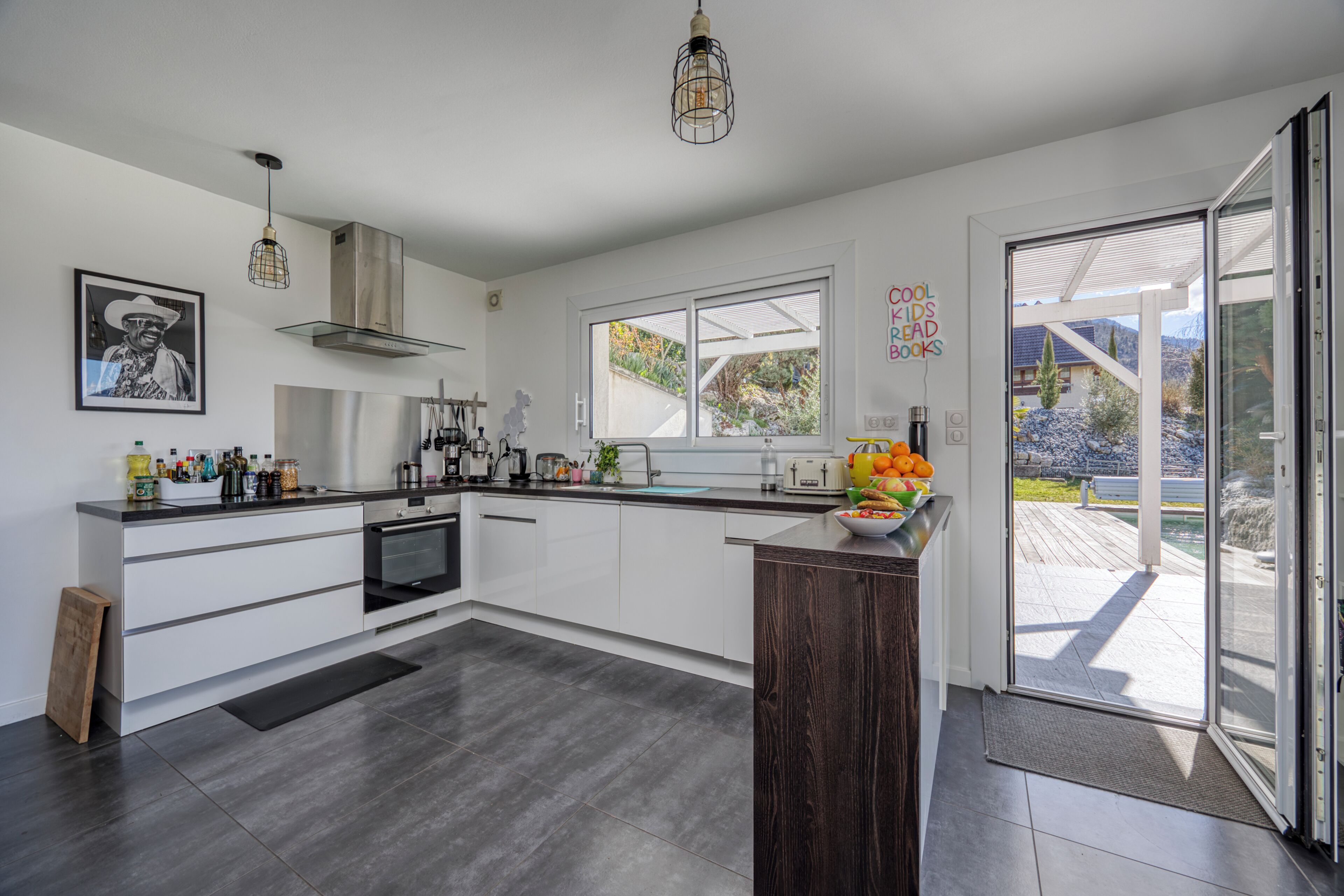 A modern kitchen with a large window, a built-in oven, and a wooden countertop.