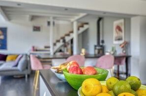 Eine moderne Küche mit einer grünen Fruchtschale, einem Zitronen Teller und einem Essbereich mit einem pinken Stuhl.