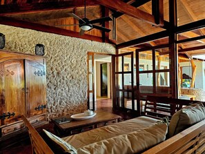 Ein rustikales Interieur mit einer Steinwand, Holzmöbeln und einem Deckenventilator.
