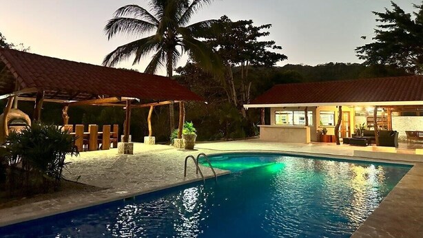 A swimming pool with a covered area, a building with a red roof, and a palm tree. - Villa Bonita – Luxury Secluded Mountain Retreat in Costa Rica (Provincia de Guanacaste)