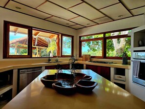 A modern kitchen with large windows, a central island, and a view of the outdoors. - Villa Bonita – Luxury Secluded Mountain Retreat in Costa Rica (Provincia de Guanacaste)
