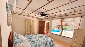 A bedroom with a bed, wardrobe, and a view of a swimming pool. - Villa Bonita – Luxury Secluded Mountain Retreat in Costa Rica (Provincia de Guanacaste)