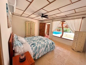 A bedroom with a bed, wardrobe, and a view of a swimming pool. - Villa Bonita – Luxury Secluded Mountain Retreat in Costa Rica (Provincia de Guanacaste)