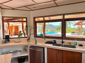 A kitchen with a view of a pool and mountains, wooden cabinets, and a coffee maker. - Villa Bonita – Luxury Secluded Mountain Retreat in Costa Rica (Provincia de Guanacaste)