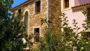 A stone building with arched windows and a pink facade. - Residence Domenique | Three-room apartment for 4 guests (Tanaunella)