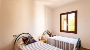 A room with two beds, a window, and a nightstand. - Residence Domenique | Three-room apartment for 4 guests (Tanaunella)