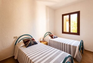 Quarto com duas camas, uma janela e uma mesa de cabeceira.