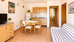 A compact living space with a dining area, kitchenette, and a bed. - Residence Domenique | Three-room apartment for 4 guests (Tanaunella)