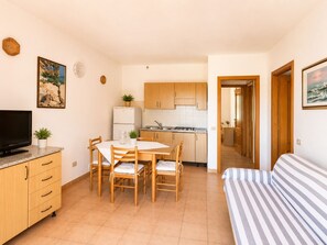 Ein kompakter Wohnbereich mit Essbereich, Küchenzeile und einem Bett.