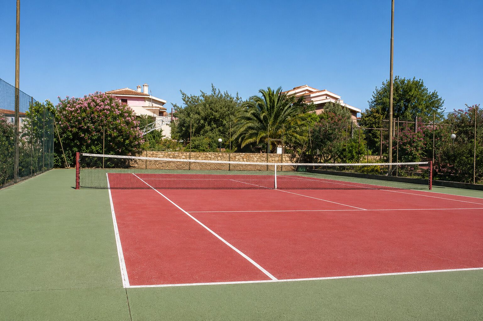 Ein Tennisplatz mit Netz, umgeben von Bäumen und Gebäuden.