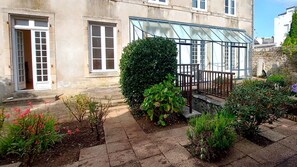 Un edificio con un invernadero, una escalera y un jardín con diversas plantas.