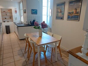 Una cocina moderna con armarios blancos, una mesa de comedor de madera y un jarrón con flores.